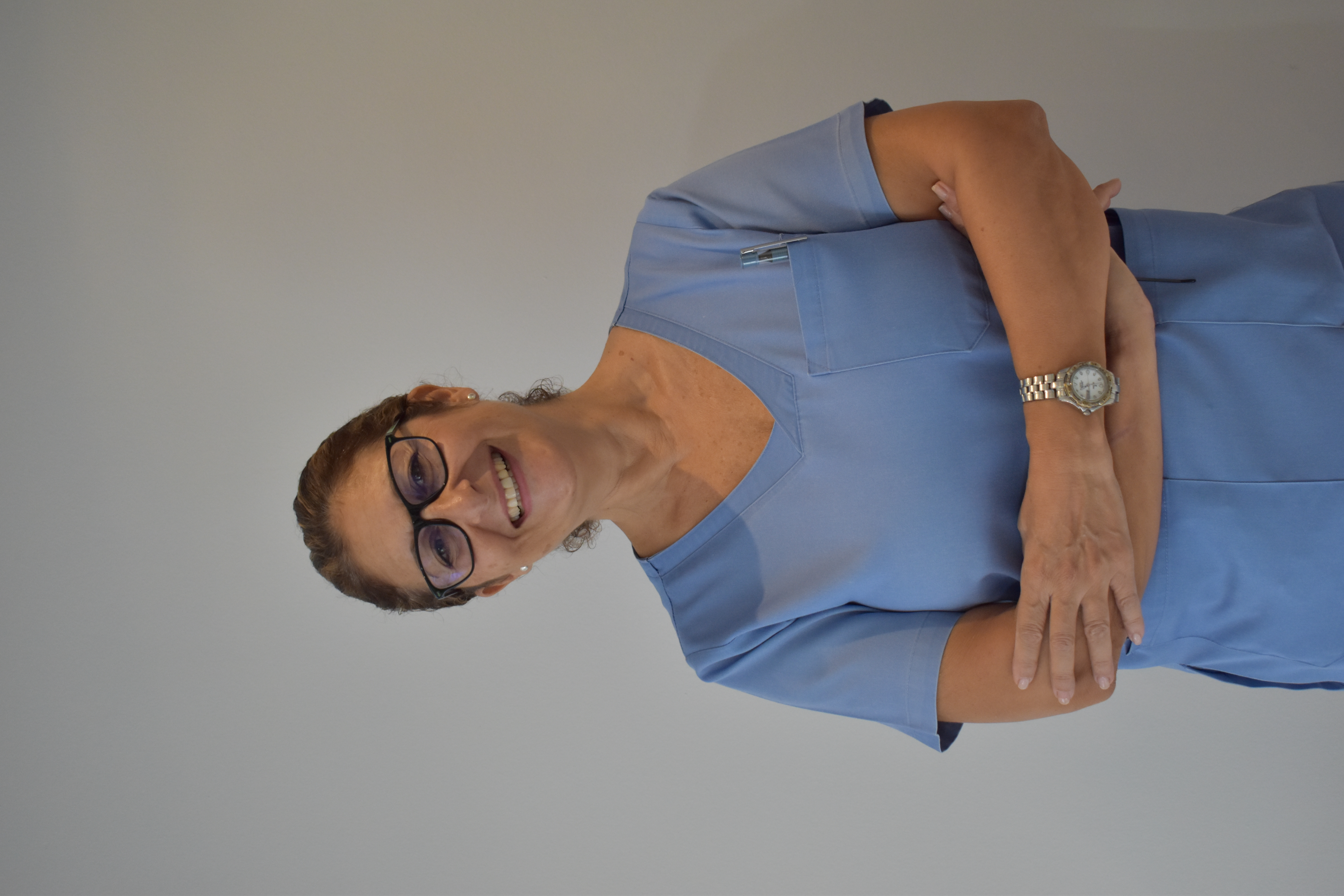 Auxiliar dental con 20 años de experiencia sonriendo en la clínica